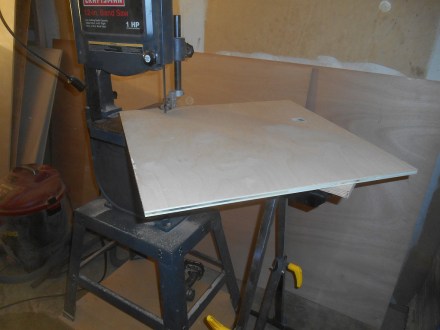 Circle maker.  Use a dowel to put a pivot at the radius you want and spin the blank around against the blade